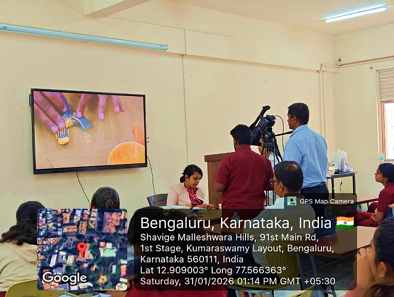 Wider view of the stage with Dr. Hemanth M speaking, and Dr. Aparna Singhal and other dignitaries seated